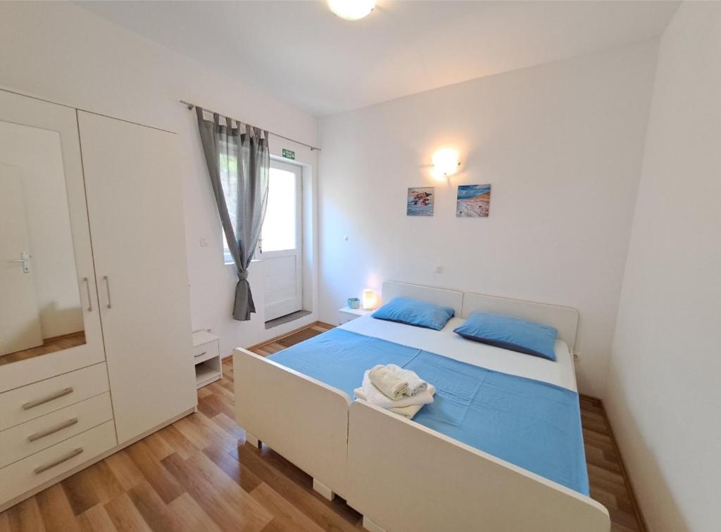 a bedroom with a bed with blue sheets and a window at Apartmani Ivano in Igrane