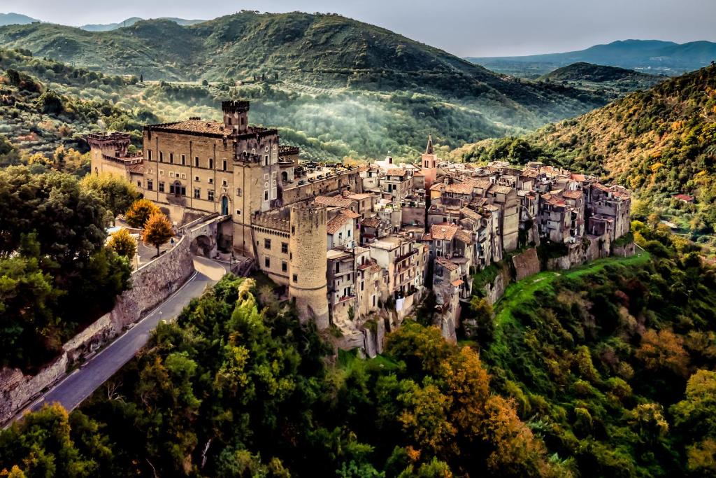un antiguo castillo en una colina con montañas en el fondo en Castello Brancaccio en San Gregorio da Sassola
