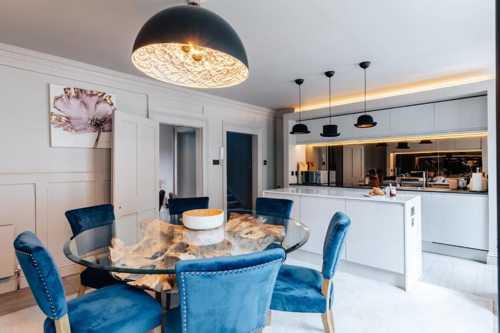 a dining room with a glass table and blue chairs at Stunning central Bath Apartment in Bath