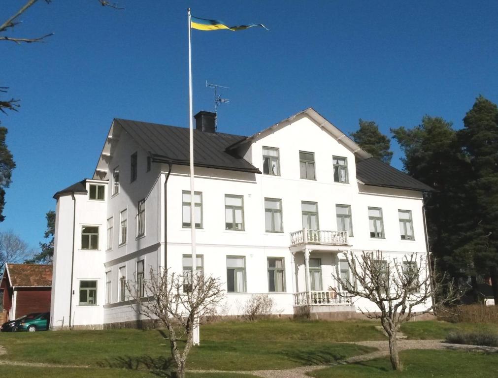 a white building with a flag on top of it at Höganlid Bed & Breakfast in Vingåker
