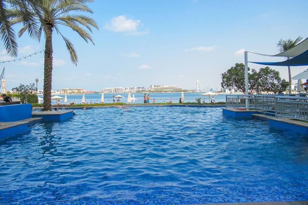 una gran piscina con palmeras y el océano en Frank Porter - Al Nabat, Shoreline 8, en Dubái