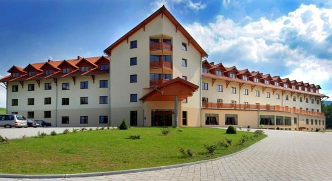 a large building with a grassy area in front of it at Ośrodek Wypoczynkowy Ariston in Miłków