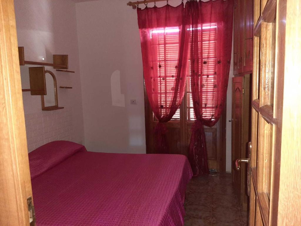 um quarto com uma cama roxa e cortinas vermelhas em Trilocale Serra Li Lioni - Sassari em Sassari