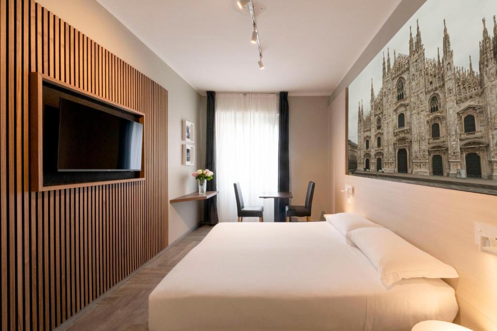 a hotel room with a bed and a flat screen tv at Kleos Hotel Milano in Milan