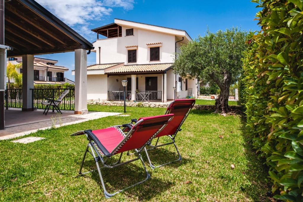 una sedia rossa seduta sull'erba di fronte a una casa di Casa Isola con Giardino by Wonderful Italy a Siracusa