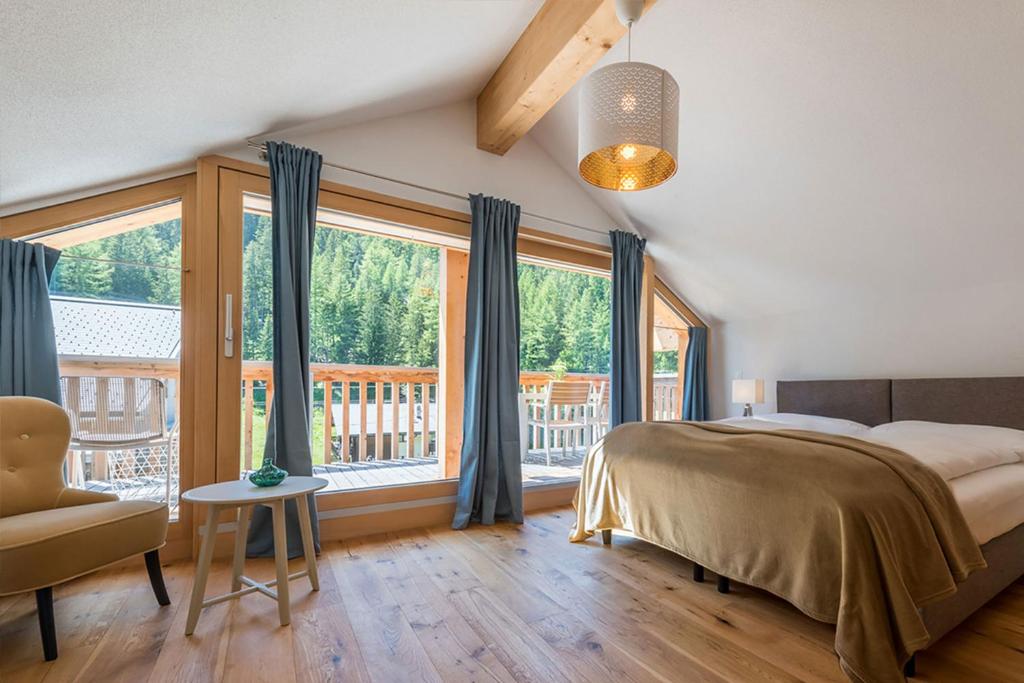 a bedroom with a bed and a large window at Montela Hotel & Resort - Suiten in Saas-Grund