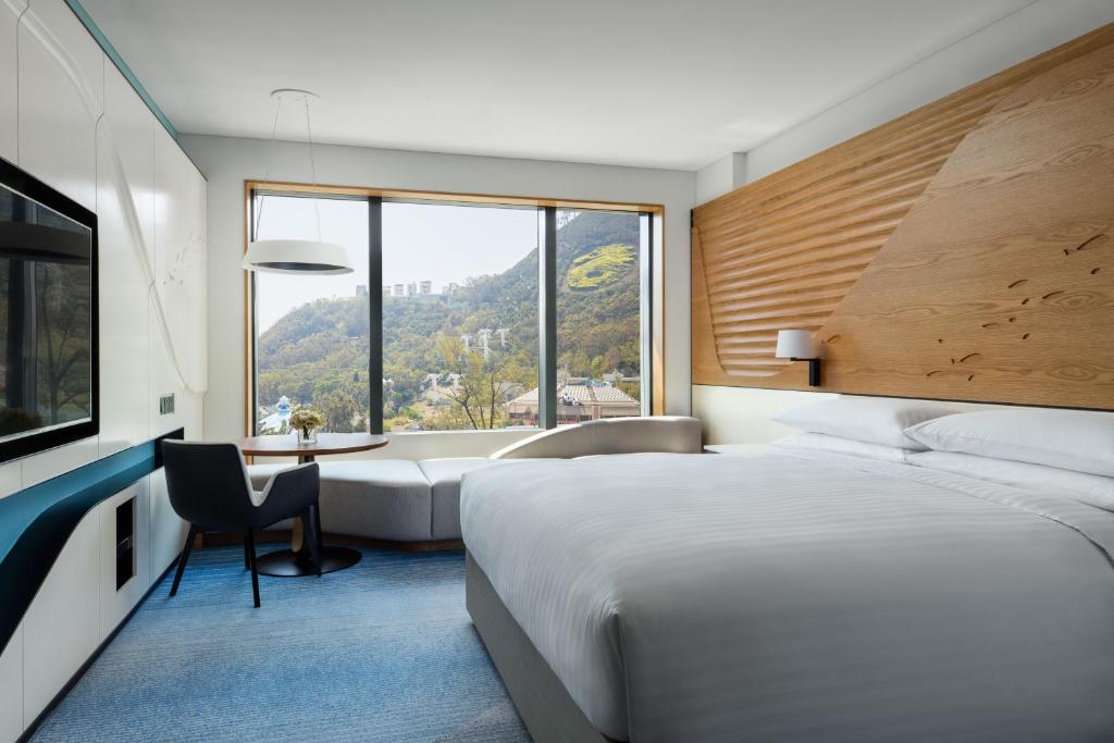 Hong Kong Ocean Park Marriott Hotel في هونغ كونغ: غرفة نوم بسرير ومكتب ونافذة