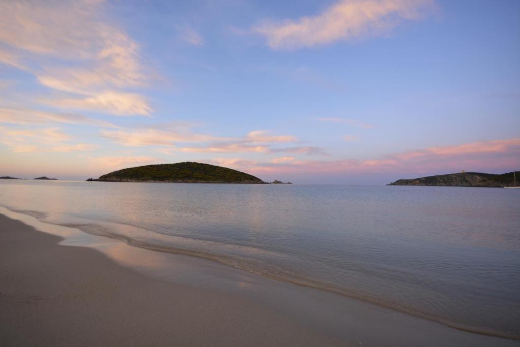 ein Strand mit zwei Inseln im Wasser bei Sonnenuntergang in der Unterkunft B&B Tanca Marracconi Teulada in Teulada