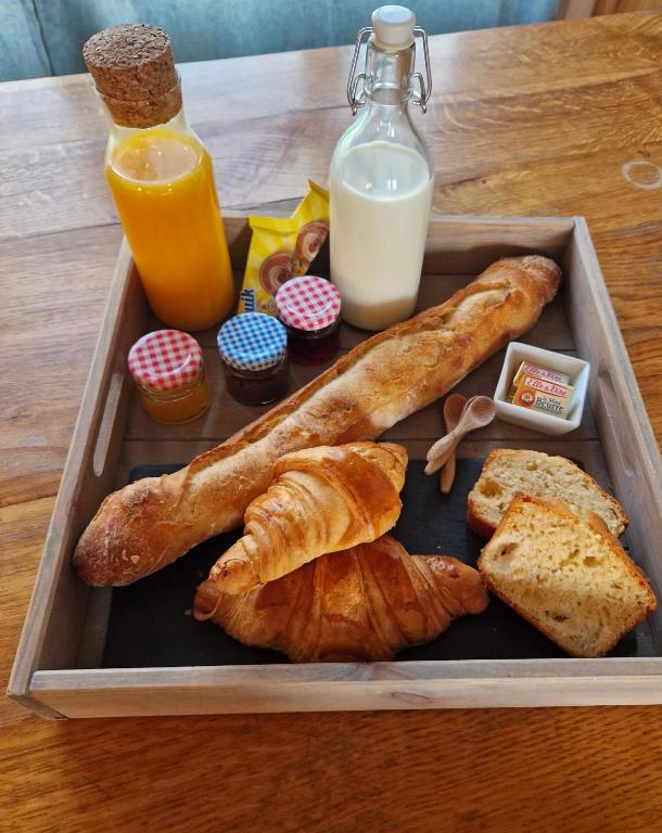 a tray of food with pastries and milk and orange juice at Le Garage in Cussy