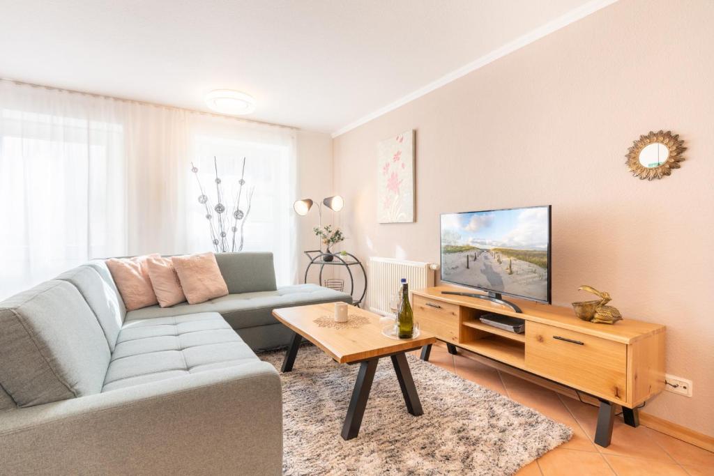 ein Wohnzimmer mit einem Sofa und einem TV in der Unterkunft Komplett neu ausgestattete Ferienwohnung für 2 Personen - mit Boxspringbett, zwei Flat-TVs und Parkplatz in Heringsdorf