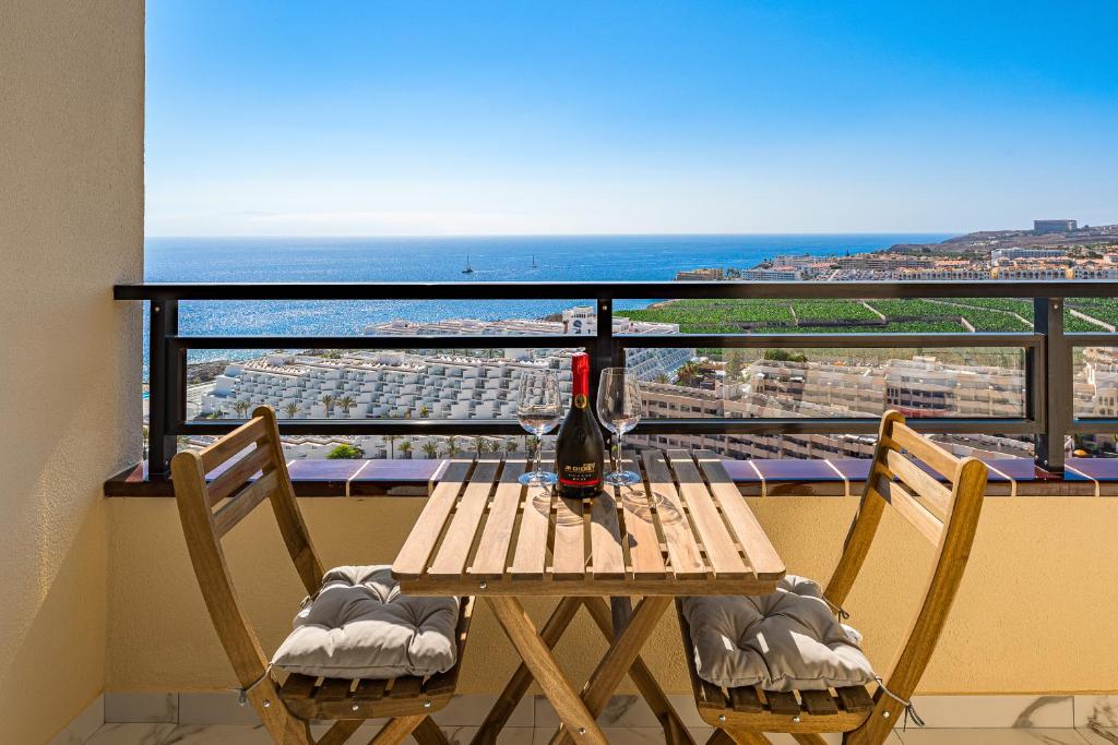 a wooden table with a bottle of wine on a balcony at Prime apartments Club Paraiso Ocean view in Playa Paraiso