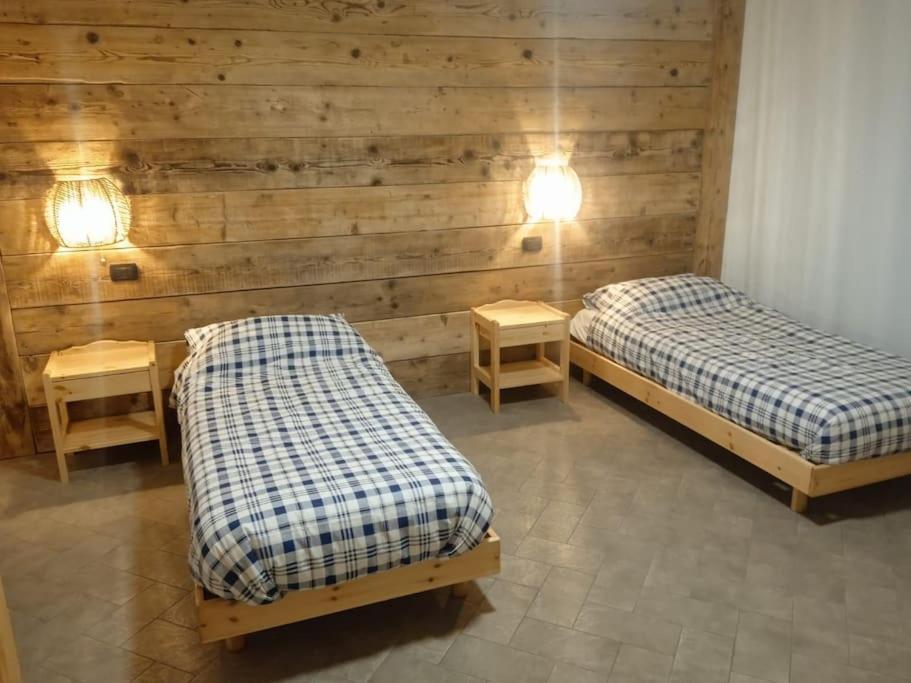 twee bedden in een kamer met houten wanden en verlichting bij Villetta in collina Casa Calmàs in Brione