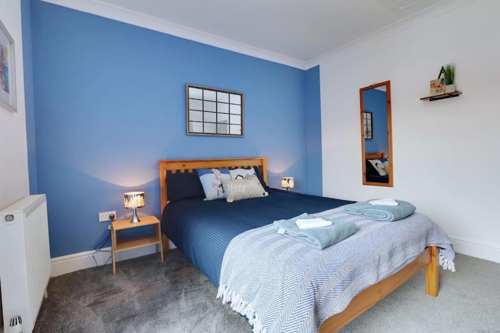 a blue bedroom with a bed with a blue wall at Cosy home by the sea in Cleethorpes