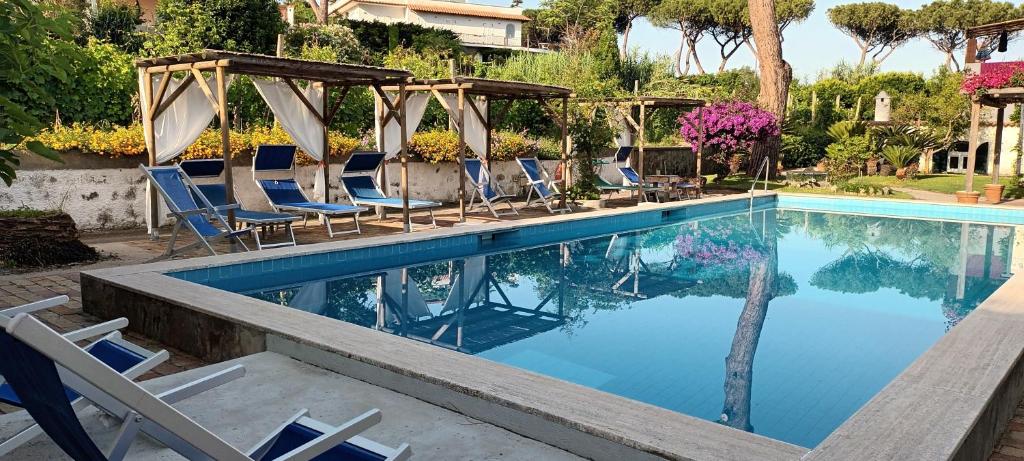 a swimming pool with chairs and a gazebo at Residence Villa Olivia in Ischia