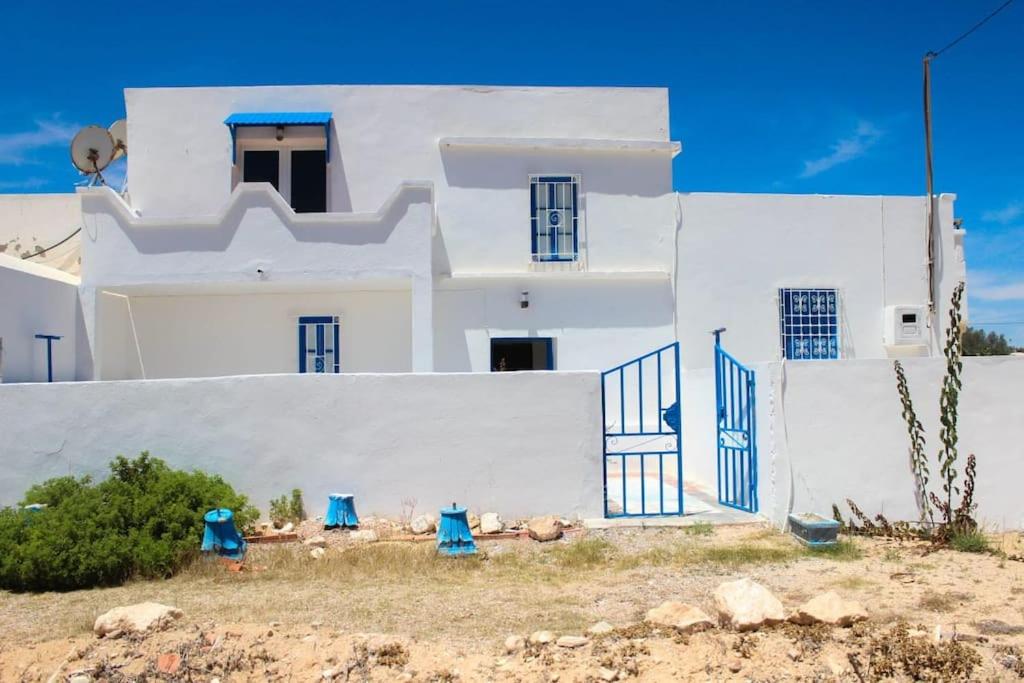 a white building with blue doors in front of it at Apartment Chez Rachida in Taguermess
