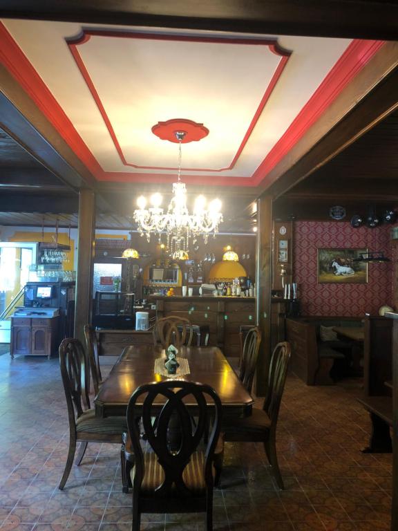 a dining room with a table and chairs and a chandelier at Holmes Café & Pension in Engelhartszell