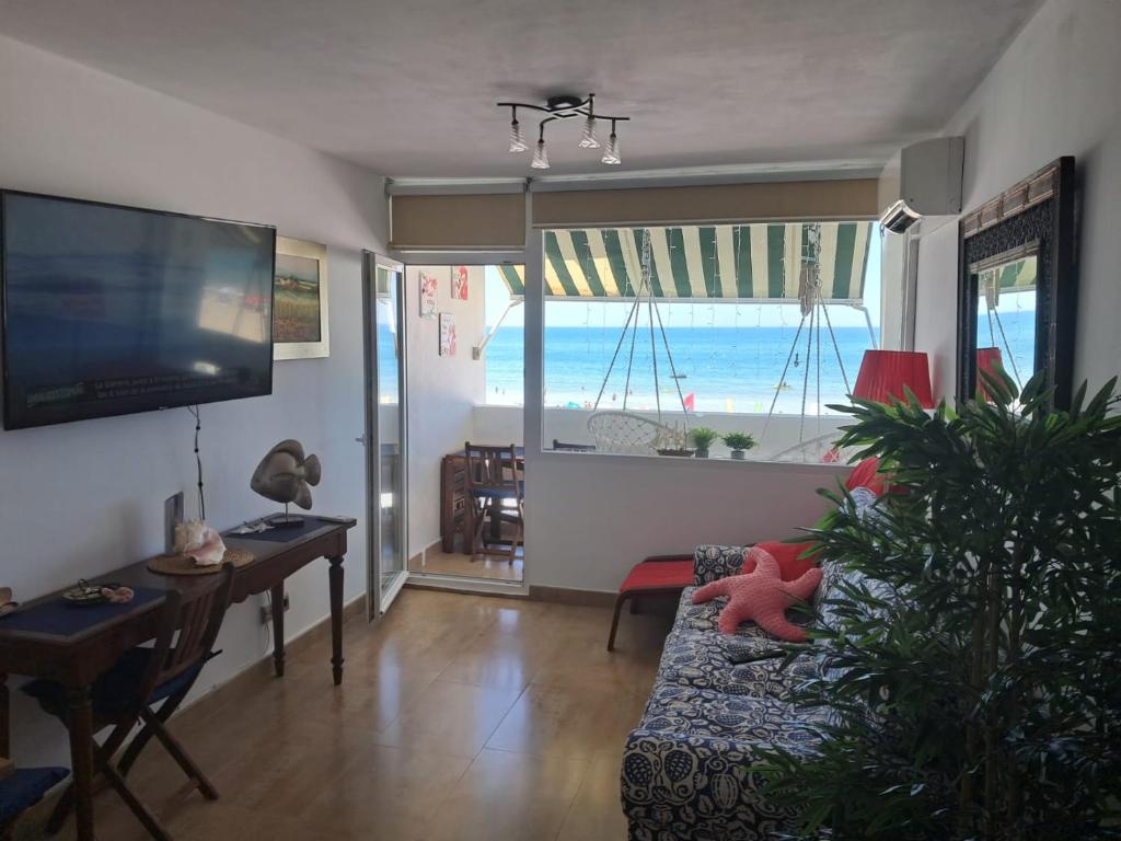 uma sala de estar com um sofá, uma mesa e uma televisão em Apartamento 108 Hotel Flamero em Matalascañas