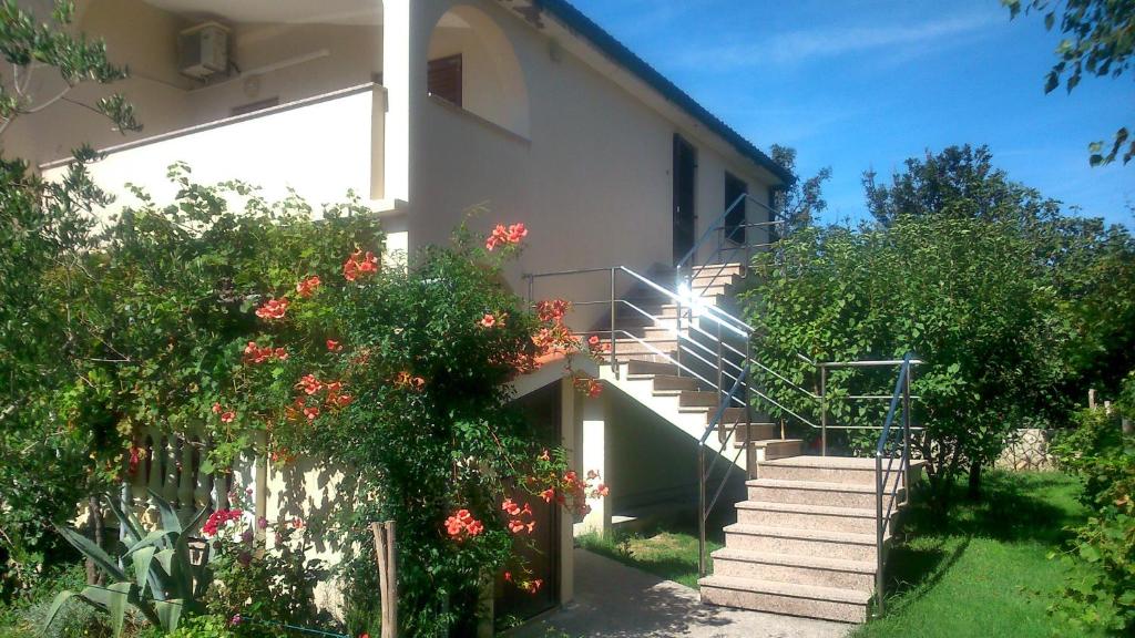a house with stairs and flowers in front of it at Apartments Vlasici in Vlašići