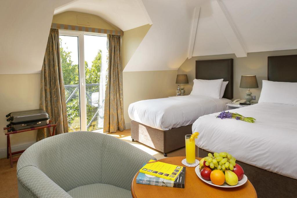 um quarto de hotel com duas camas e uma mesa com uma tigela de fruta em Hylands Burren Hotel em Ballyvaughan