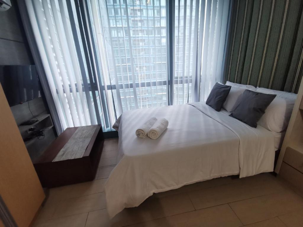 ein Schlafzimmer mit einem großen Bett mit zwei Handtüchern darauf in der Unterkunft Sunshine Properties at One Uptown BGC in Manila