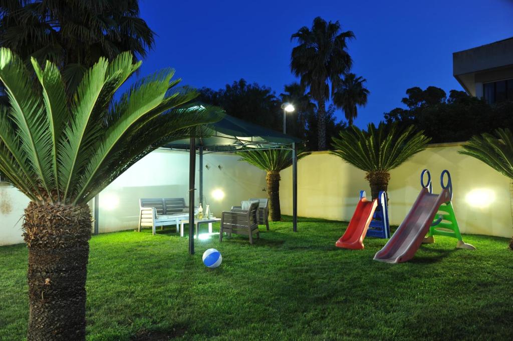 einen Hof mit einem Spielplatz mit zwei Rutschen und Palmen in der Unterkunft B&B Erminia in Presicce