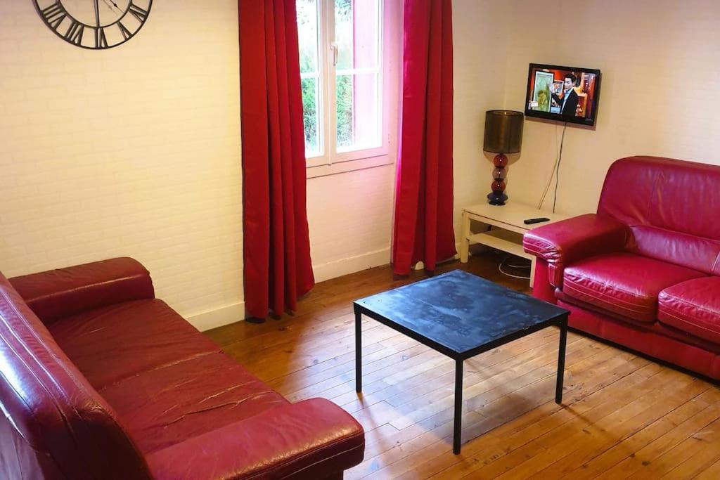 un salon avec un canapé rouge et une table dans l'établissement Maison lumineuse & jardin privé, à Confolens