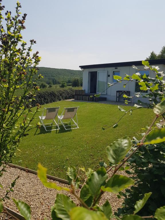 two chairs sitting on a lawn in front of a house at O'Blanche, Viroinval Treignes in Treignes