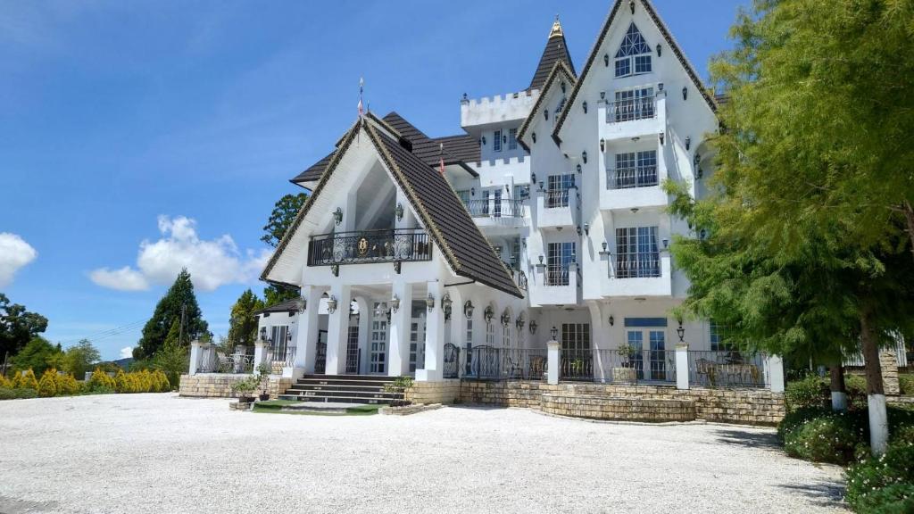 une grande maison blanche avec une grande allée. dans l'établissement Arts Castle, à Renai