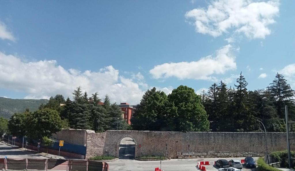 una pared de piedra con un túnel y árboles y coches en Hotel Porta Rivera Plesso Stazione, en LʼAquila