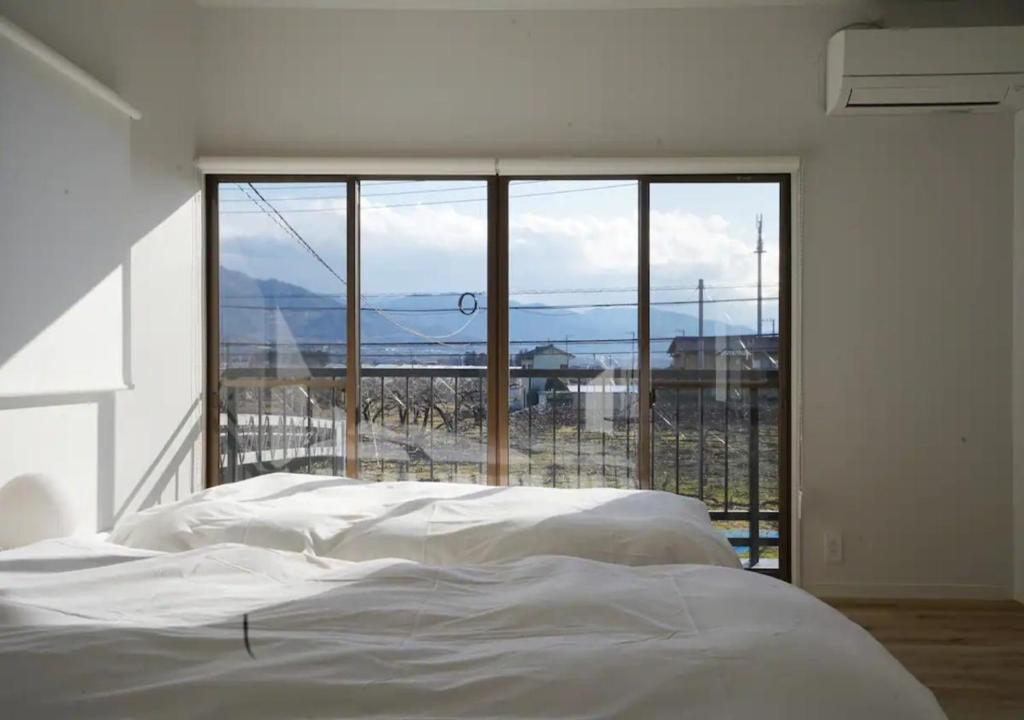 1 dormitorio con cama blanca y ventana grande en Kajitsuno mieru yado - Vacation STAY 06979v, en Koshu