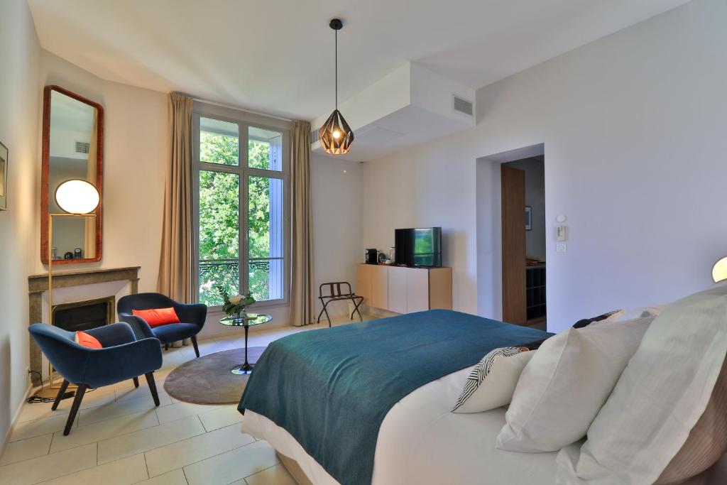 a bedroom with a bed and a chair and a fireplace at Villa Meridia in Nîmes