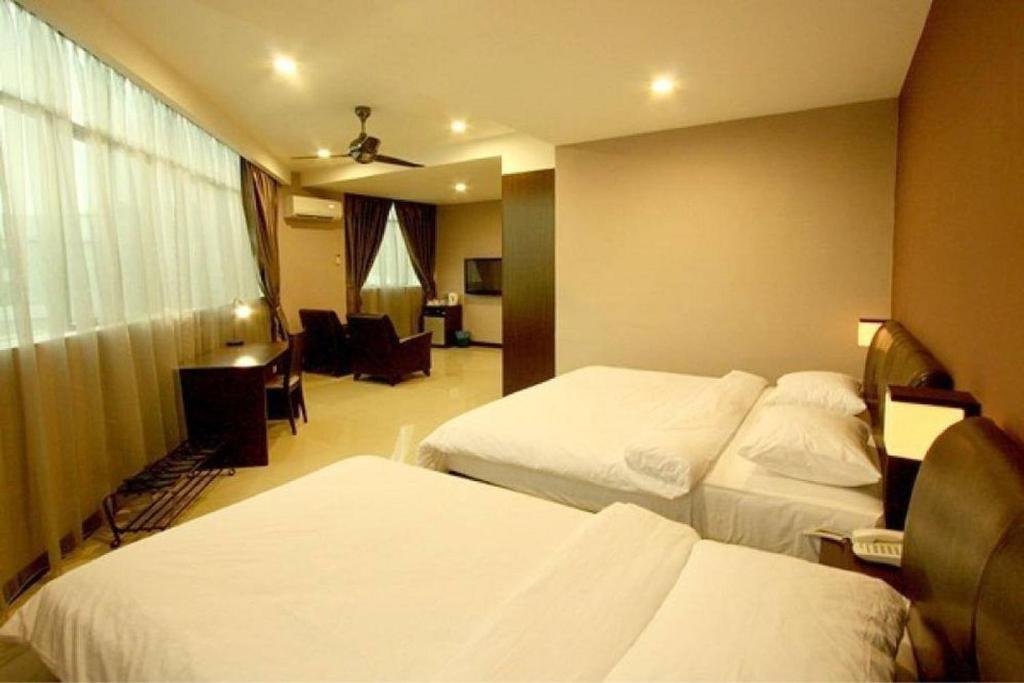 Cette chambre comprend deux lits et un bureau. dans l'établissement Capital O 90767 Rail Hotel, à Keluang