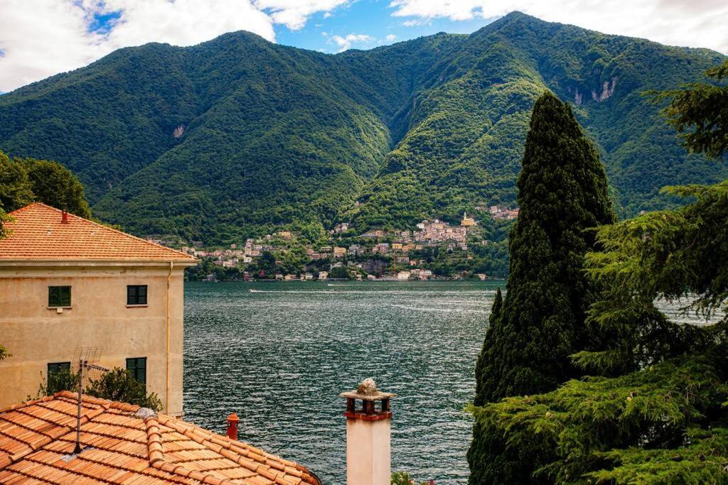 a building next to a body of water with mountains at Lemon Tree Lake View - by MyHomeInComo in Laglio