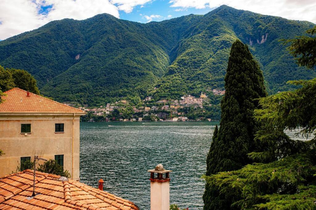 un edificio junto a un cuerpo de agua con montañas en Lemon Tree Lake View - by MyHomeInComo en Laglio