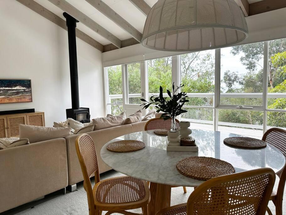 ein Wohnzimmer mit einem Tisch und einem Sofa in der Unterkunft Seaview Treehouse - three minute walk to the beach in Lorne