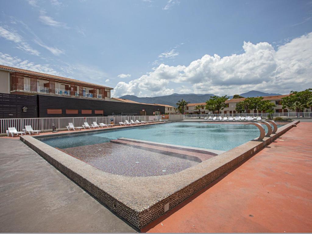 une piscine avec des chaises longues et un bâtiment dans l'établissement Vacancéole - Les demeures de la Massane - Argelès-sur-Mer, à Argelès-sur-Mer