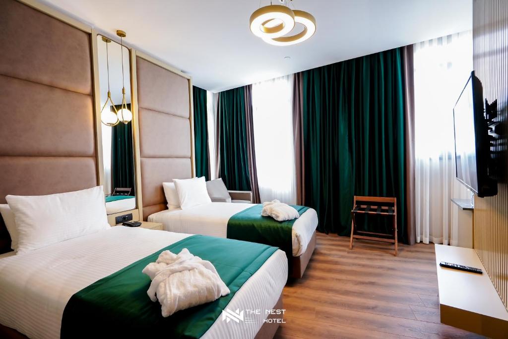 two beds in a hotel room with green curtains at THE NEST HOTEL in Istanbul