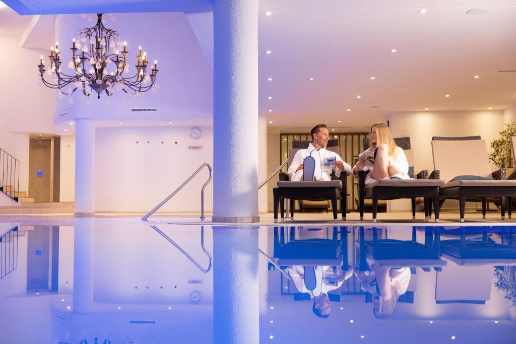 サースフェーにあるWalliserhof Grand-Hotel & Spa Relais & Châteauxのプール付きの客室で、椅子に座って2名が宿泊できます。