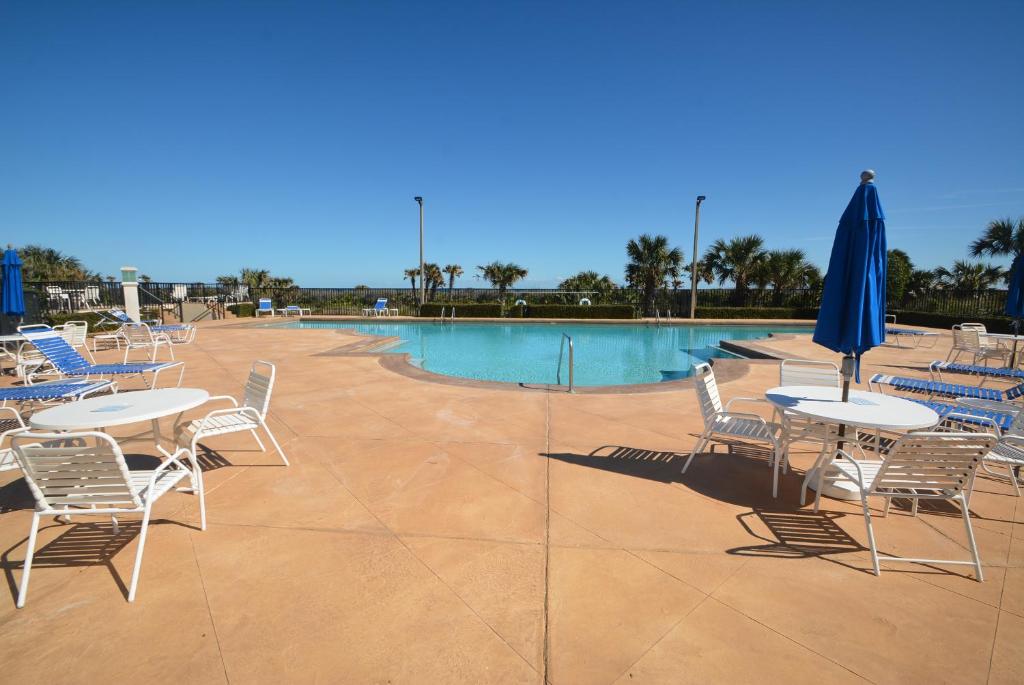 a patio with tables and chairs and a swimming pool at Surf Club I, 1405 in Marineland