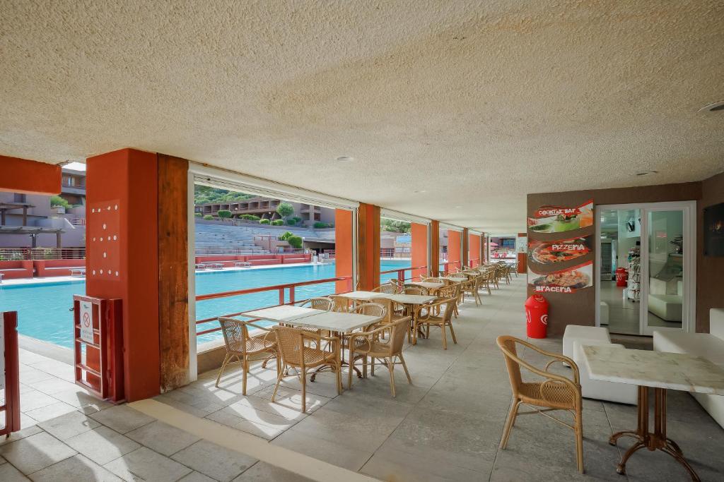 un restaurante con mesas y sillas junto a una piscina en Casa Vacanza Tramontana 2414, en Cugnana