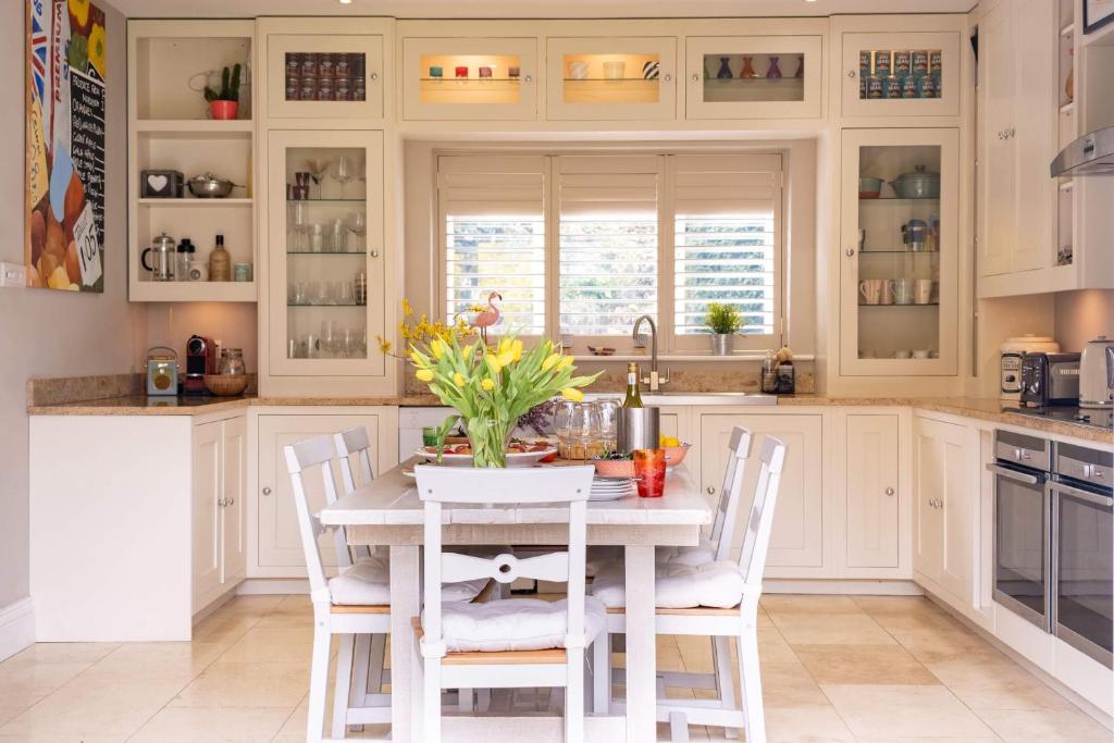 a kitchen with white cabinets and a table with chairs at Sway Corner in Lymington