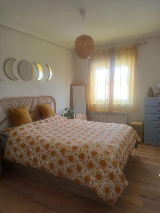 um quarto com uma cama com um cobertor laranja e branco em Apartamento en Plentzia en barrio muy tranquilo con aparcamiento gratuito y al lado del metro em Elejalde