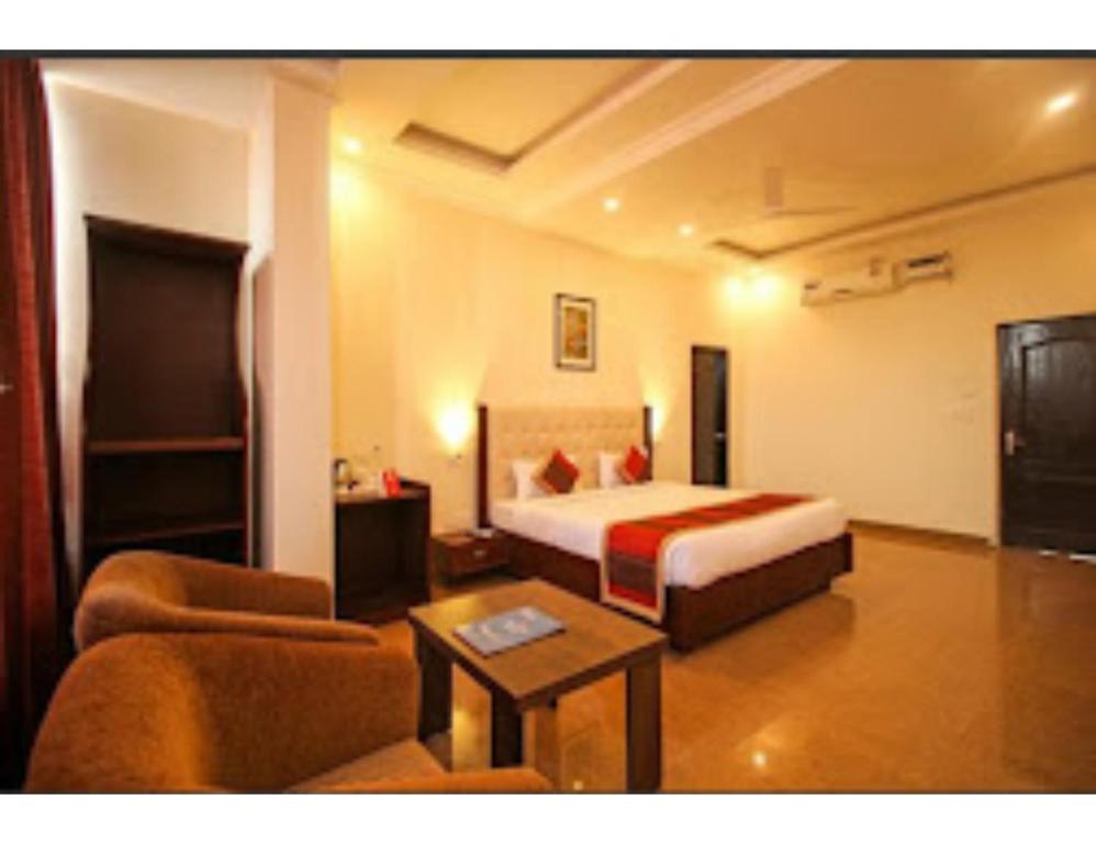 Shiva Farm, Hotel Baramasa By Welinna Group, Dehradun في دهرادون: غرفه فندقيه بسرير واريكه