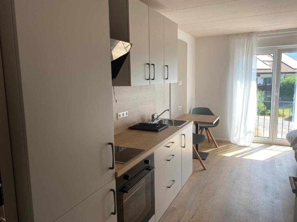eine Küche mit weißen Schränken, einer Spüle und einem Tisch in der Unterkunft Obstbau Apartment am See in Lindau