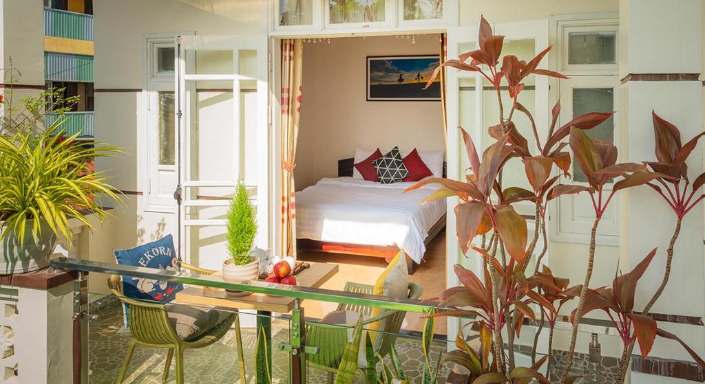 1 dormitorio con 1 cama y balcón con plantas en Strawberry Garden Homestay, en Hoi An