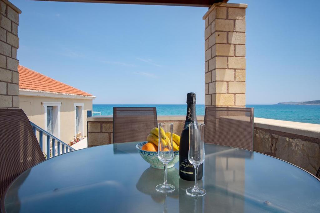 a glass table with a bottle of wine and a bowl of fruit at Villa Anastasia Kalyves in Kalyves