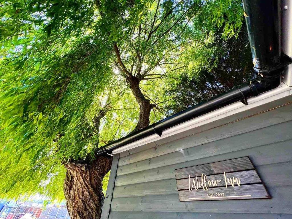 una señal en el lado de un edificio con un árbol en Willow Inn, en Kent