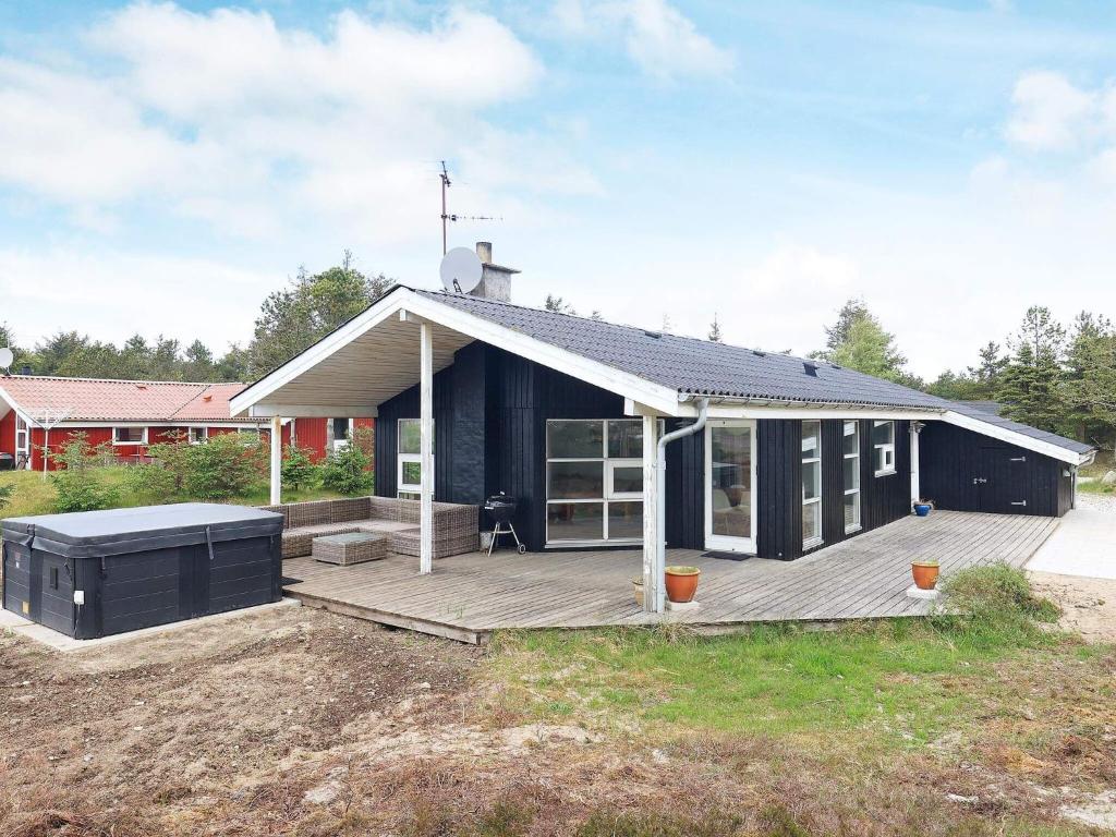 Sønder Vorupørにある8 person holiday home in Thistedの庭にデッキのある黒い家