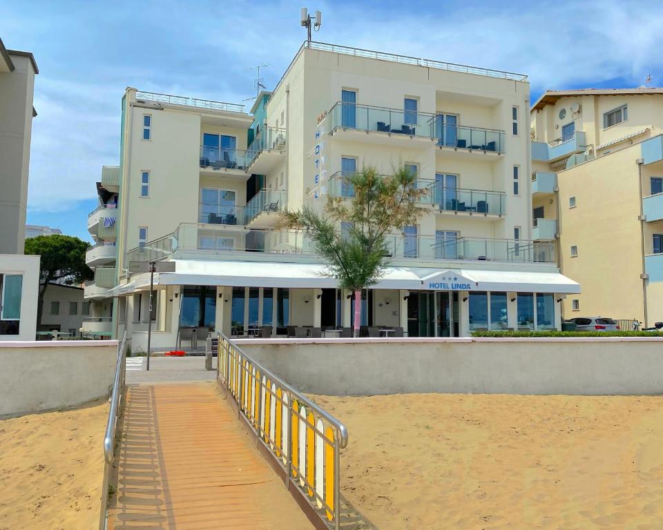 a building on the beach with a boardwalk in front of it at Hotel Linda in Caorle