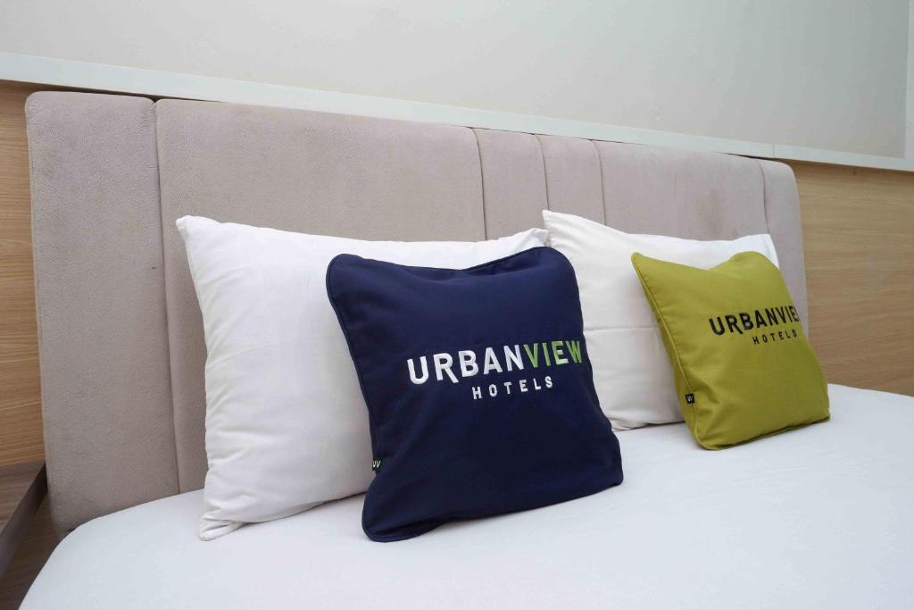 - un ensemble d'oreillers assis au-dessus d'un lit dans l'établissement Urbanview Hotel Double Tree Purwokerto by RedDoorz, à Purwokerto